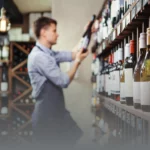 A photo of a man placing a wine bottle onto a rack.