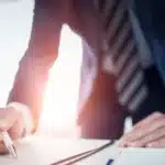 A photo of a man signing a document.