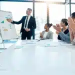 A photo of a group of people in a meeting clapping.